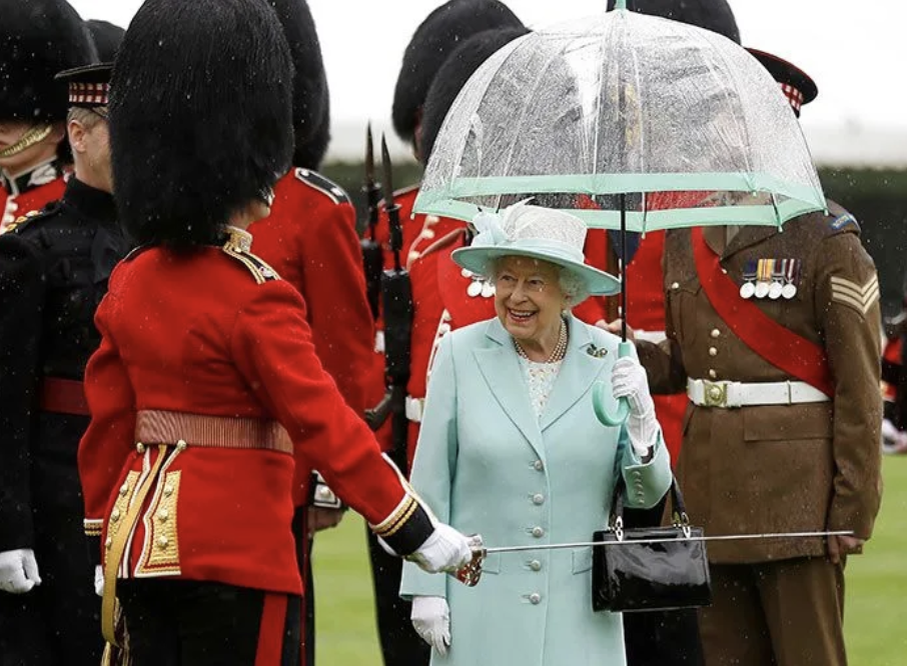  Королева Елизавета II и ее аксессуары. Какие ассоциации? Первое – черные сумочки, второе – белые перчатки, третье – прозрачные зонтики с цветной полосой.-7