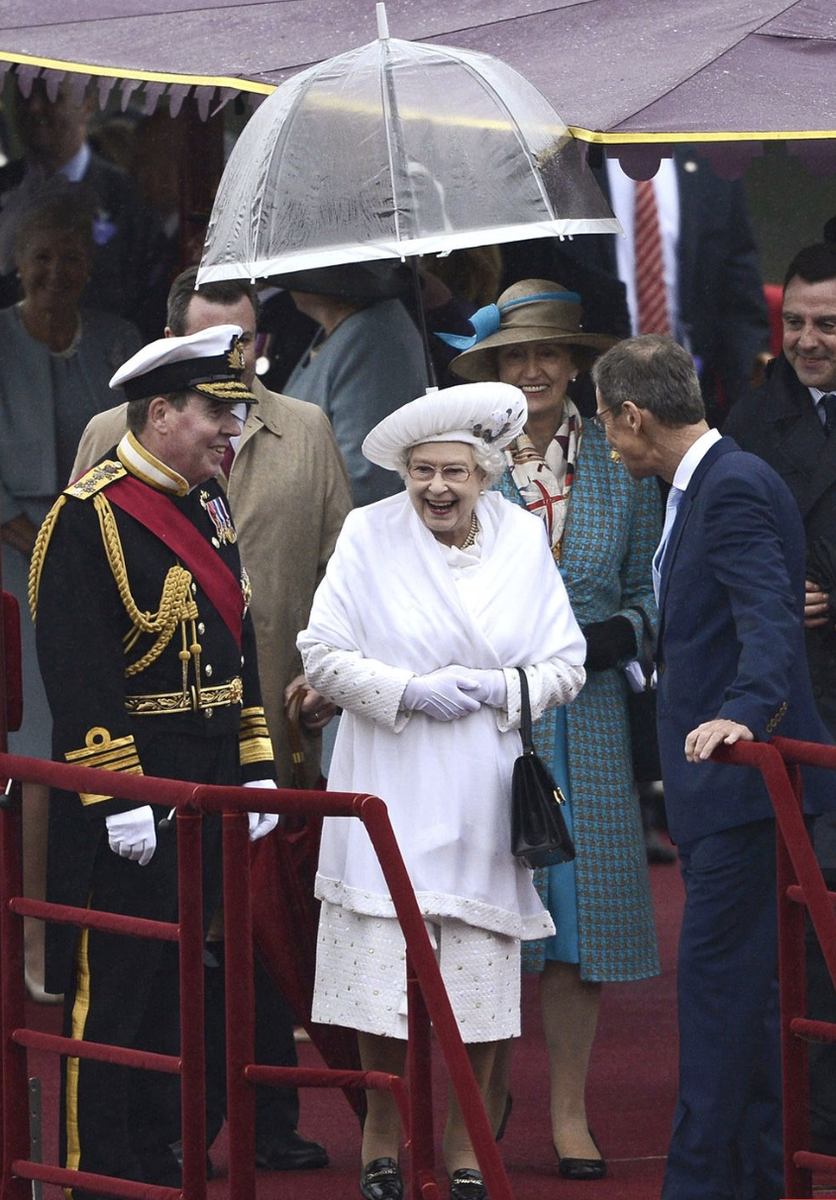  Королева Елизавета II и ее аксессуары. Какие ассоциации? Первое – черные сумочки, второе – белые перчатки, третье – прозрачные зонтики с цветной полосой.-17