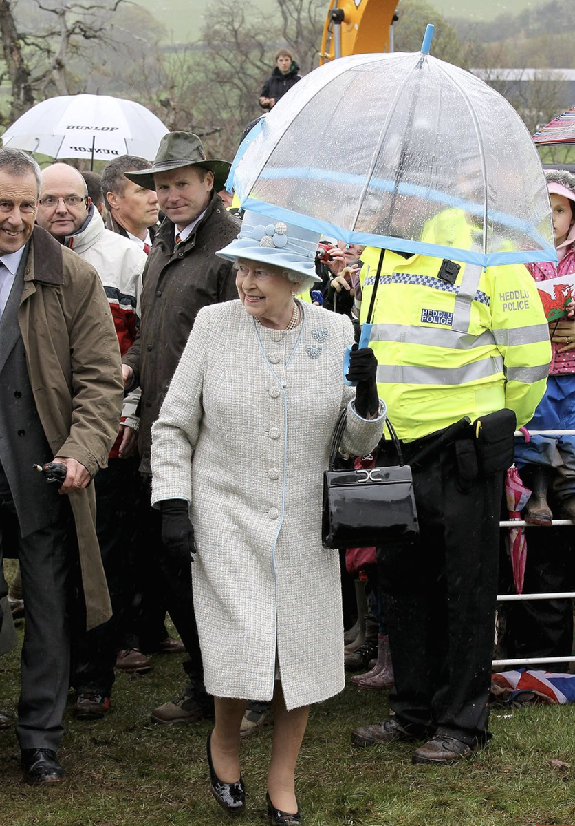  Королева Елизавета II и ее аксессуары. Какие ассоциации? Первое – черные сумочки, второе – белые перчатки, третье – прозрачные зонтики с цветной полосой.-19