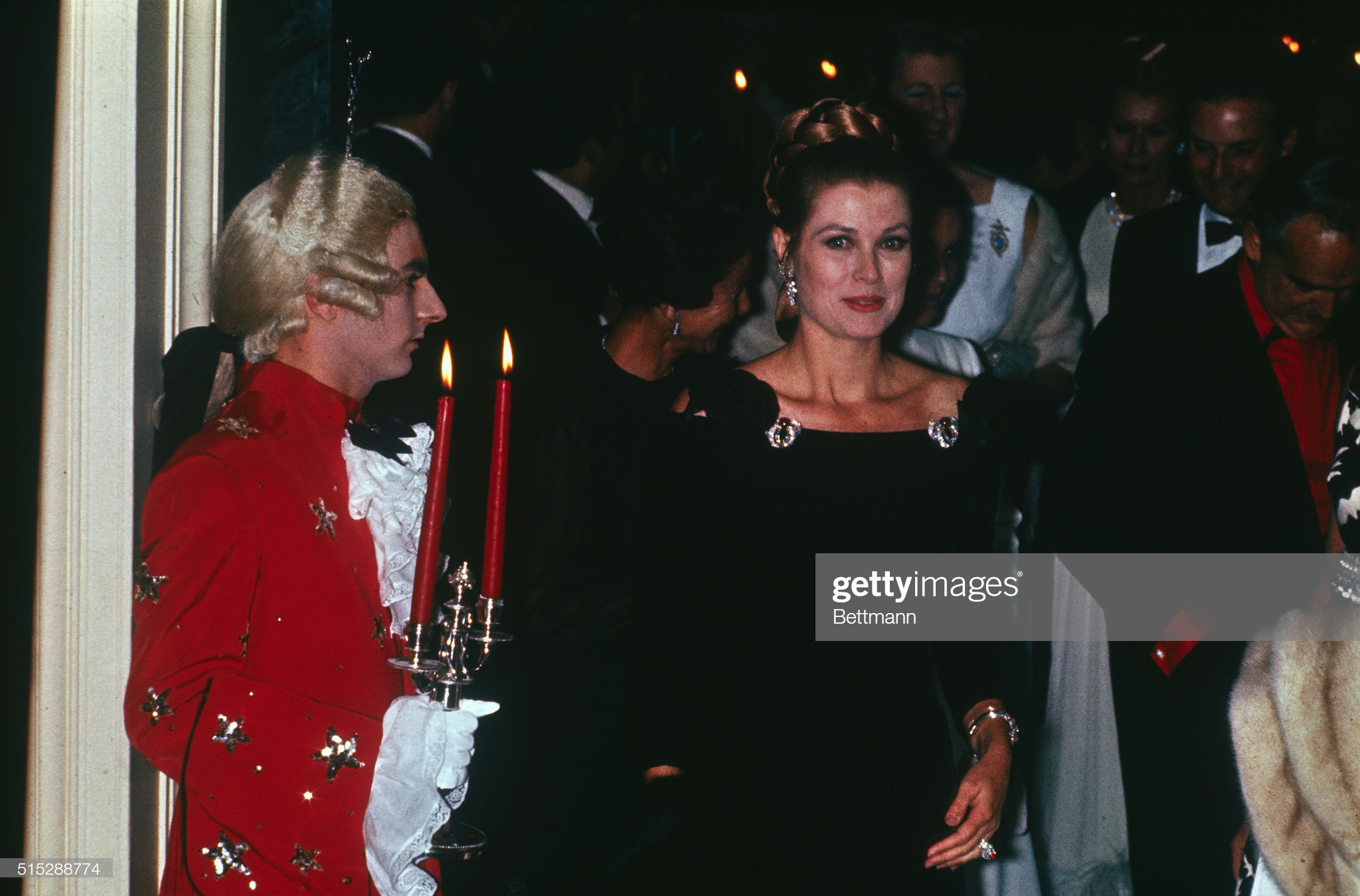  Принцесса Грейс в черном бархатном платье Баленсиага в отеле «Эрмитаж», Париж, в 1969 году, где праздновали ее 40-летие. Рубиновый кабошон и броши с бриллиантами, которые она использовала для украшения платья в 1969 году, были съемными деталями из монакской тиары Bains de Mer, разработанной Картье.  Также на Грейс соответствующее рубиновое кольцо.